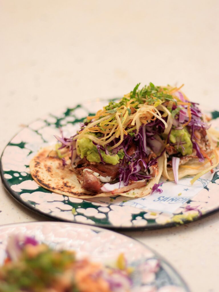 Delicious fish taco garnished with vibrant cabbage and guacamole, set in a Mexican style.